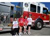 Nora Tarello, joined by friends, stands beside a Smithtown Fire Department engine after arriving at Mt. Pleasant Elementary School through a special fundraiser experience.  