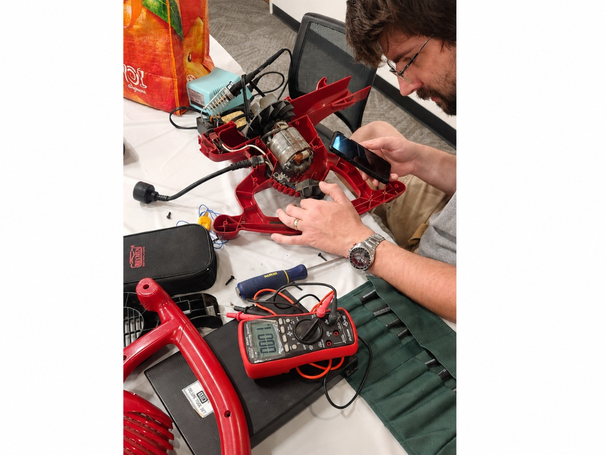A volunteer examines the inner workings of a broken appliance during the Long Island Repair Café at Huntington Public Library on Aug. 8.