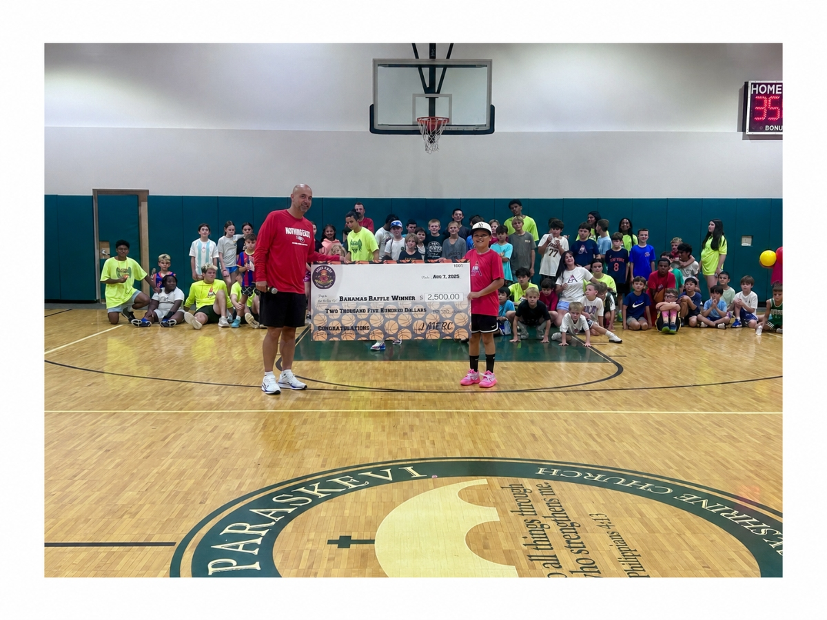 MERC Basketball Camp founder Jason Mercurio, left, and 10-year-old camper Jordan Sprague pose with a ceremonial $2,500 Bahamas raffle check as campers gather behind them on the final day of the camp’s 20th anniversary season in Greenlawn.