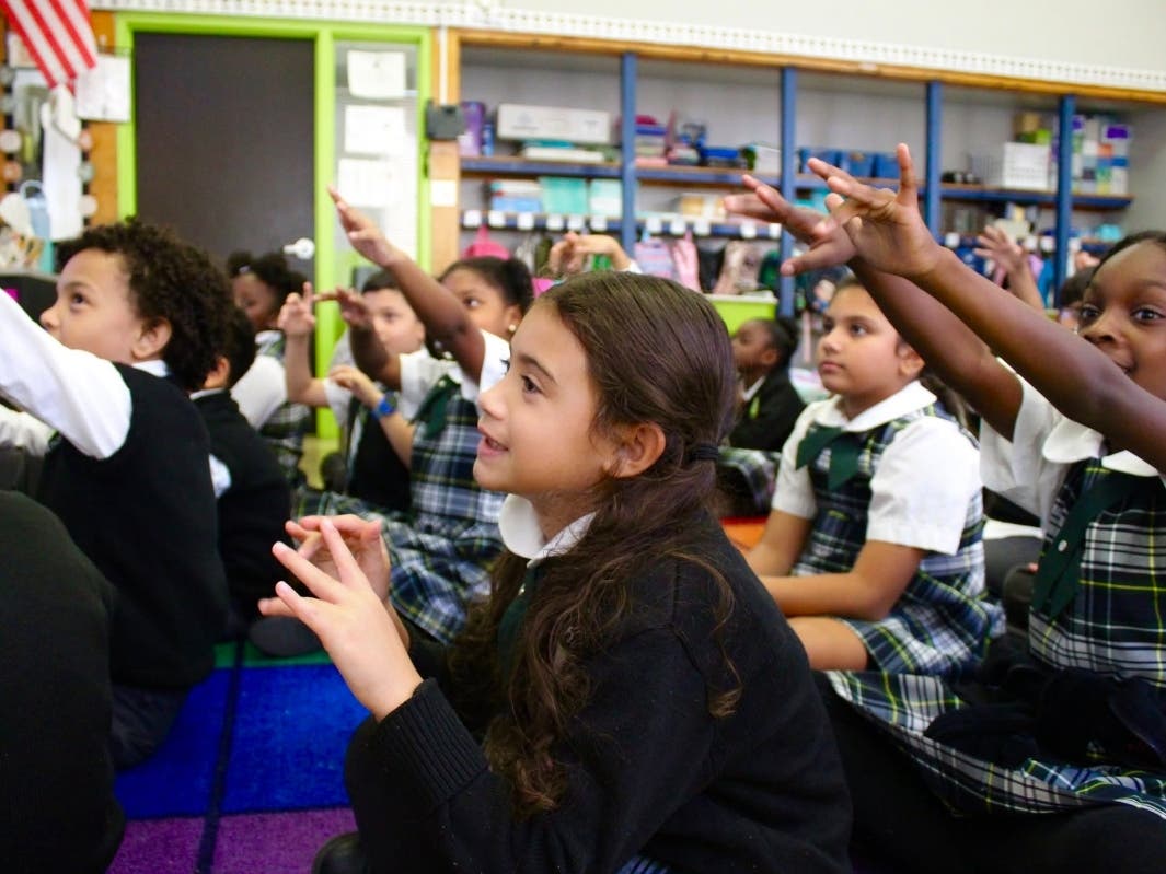 South Shore Charter School students raise their hands during a classroom lesson.