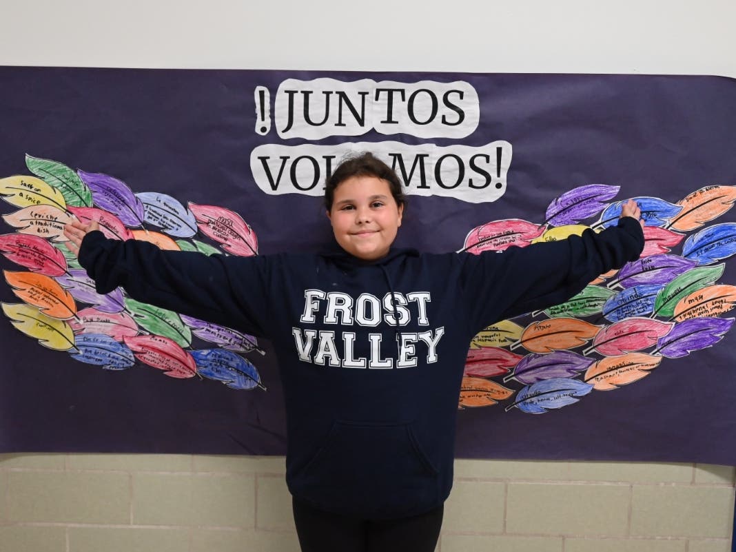 An Udall Road Middle School student poses in front of the school's "¡Juntos Volamos!" — or "Together, We Fly!" — mural.