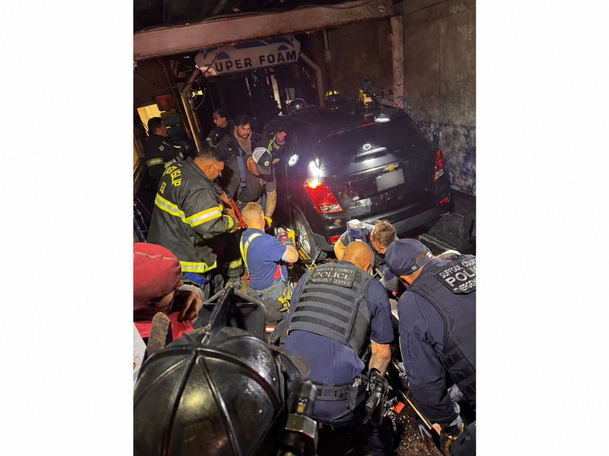 East Islip firefighters and Suffolk County police emergency service officers work to free a man whose leg became trapped in a car wash roller Thursday afternoon.