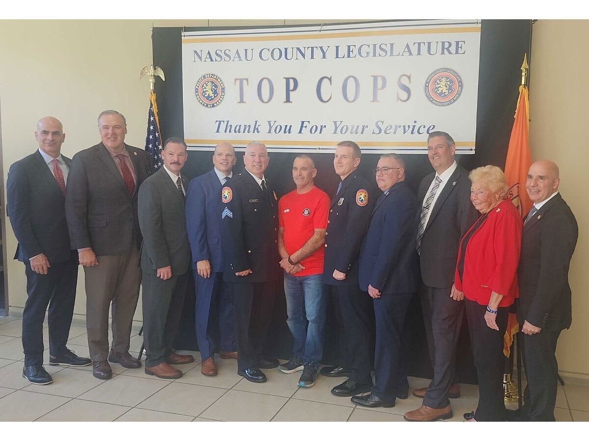 Nassau County Police Sgt. Frederick Tifaro and Officer Brian Sujka stand alongside referee Vito Cassara (center, red shirt), Nassau County officials and police union representatives during a ceremony honoring the officers for helping save Cassara's life a