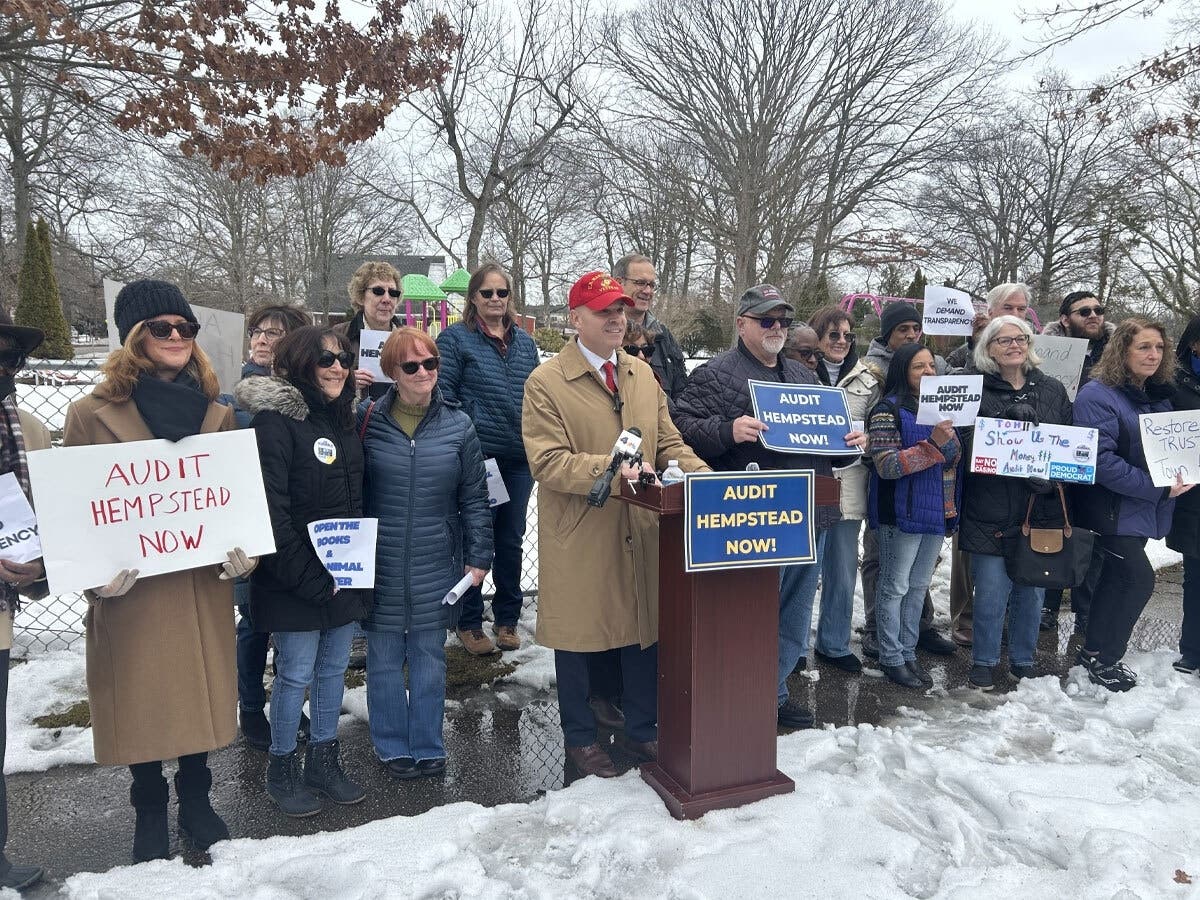 Joe Scianablo (center, red hat) called for an audit of the Town of Hempstead's finances Thursday, flanked by residents of the town. 