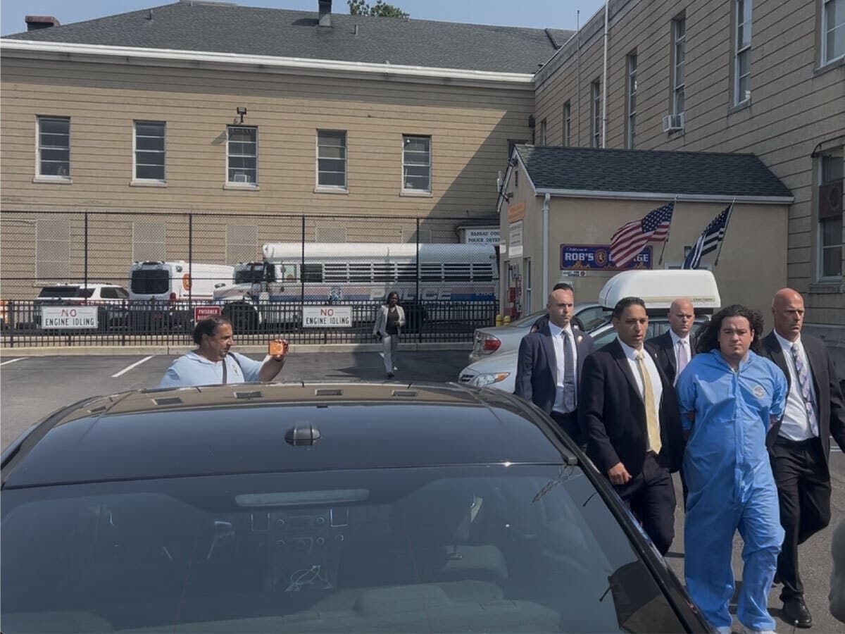 Joseph Horner (right, in blue) is escorted to his arraignment by Nassau County police. 