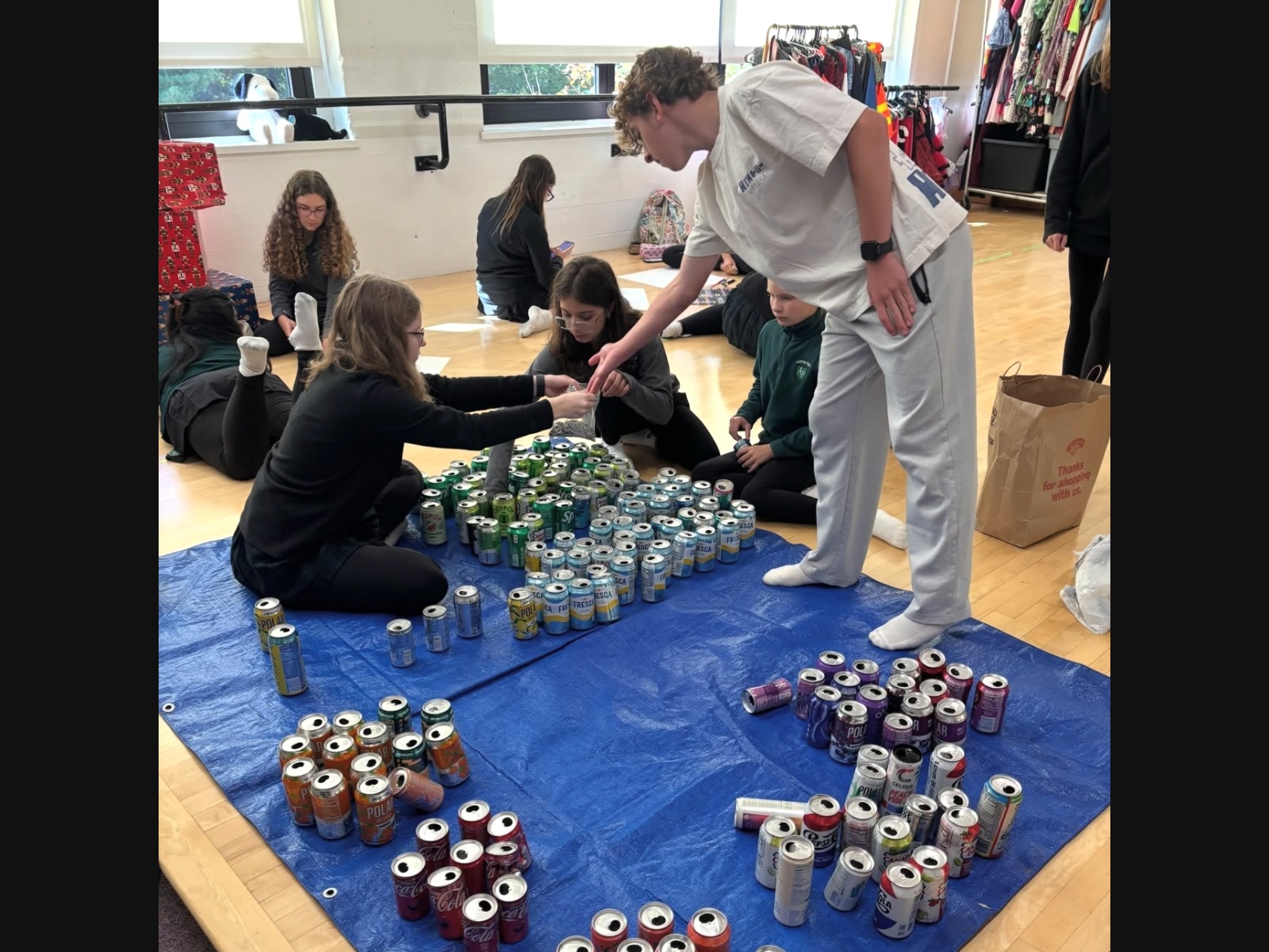 From left, Anna Beaumier ’28 (of Andover), Angie Bates ’33, (of Melrose), Karaline Linder ’33 (of Andover), and Jackson Lowndes ’31 (of Stoneham) create props from collected cans for the Austin Prep Drama Club production of Haters.