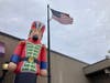 A giant inflatable nutcracker decoration next to an flag pole with the American flag in Hillsborough, NJ