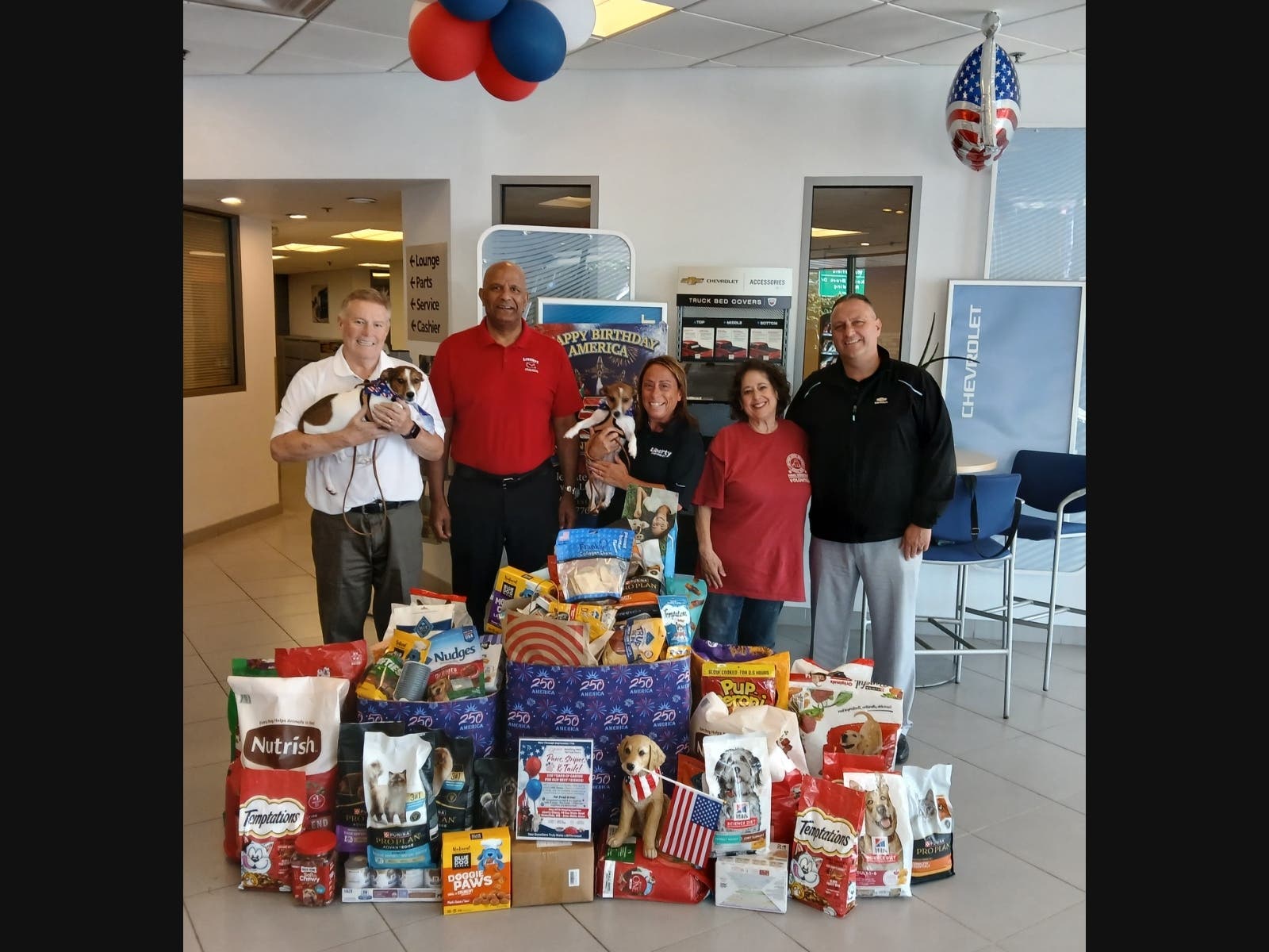 PAWS President Robin Gorfine, in red t-shirt, meets with Liberty Chevrolet and looks over food items collected for the PAWS Food Pantry.