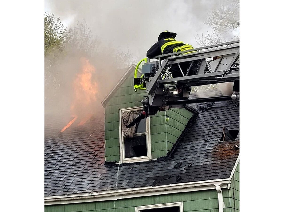 A Woburn firefighter approaches a second-story blaze Saturday from the city's new Ladder 2 apparatus. 