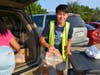 Brad Bai taking food to neighbors cars at the Seven Loaves Food Pantry 