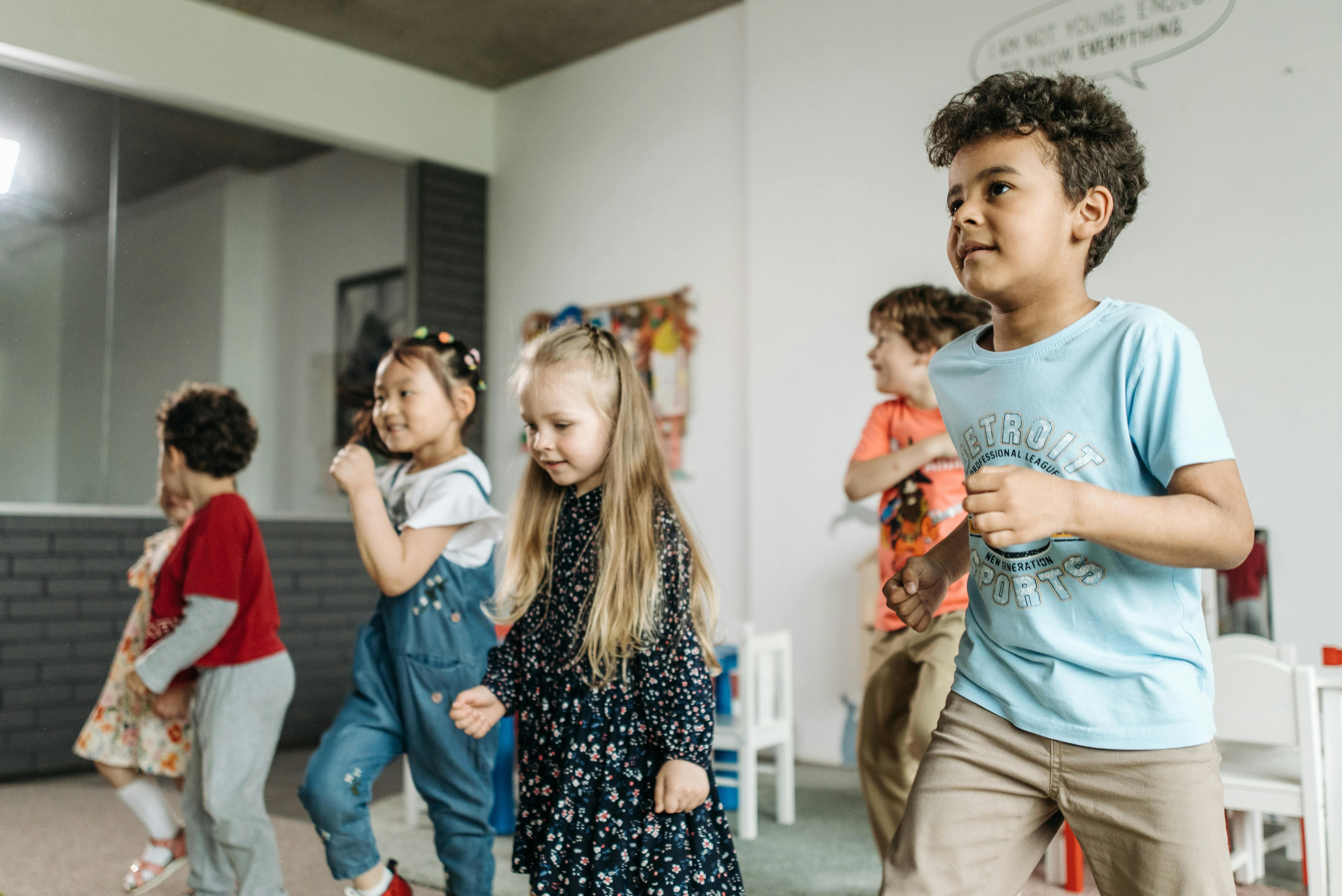 School-age children dancing in a bright classroom, concentrating and smiling.