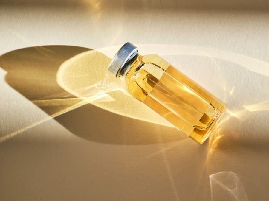 Injection vial with medicinal product in sunlight on beige background.
