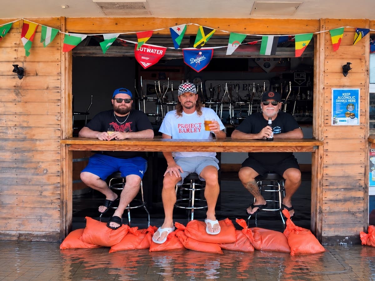 The beer keeps flowing at Project Barley Taps and Grill in Redondo Beach, where three men make the best of rising seawater behind a makeshift sandbag barrier along the International Boardwalk on Tuesday, Oct. 27, 2026.