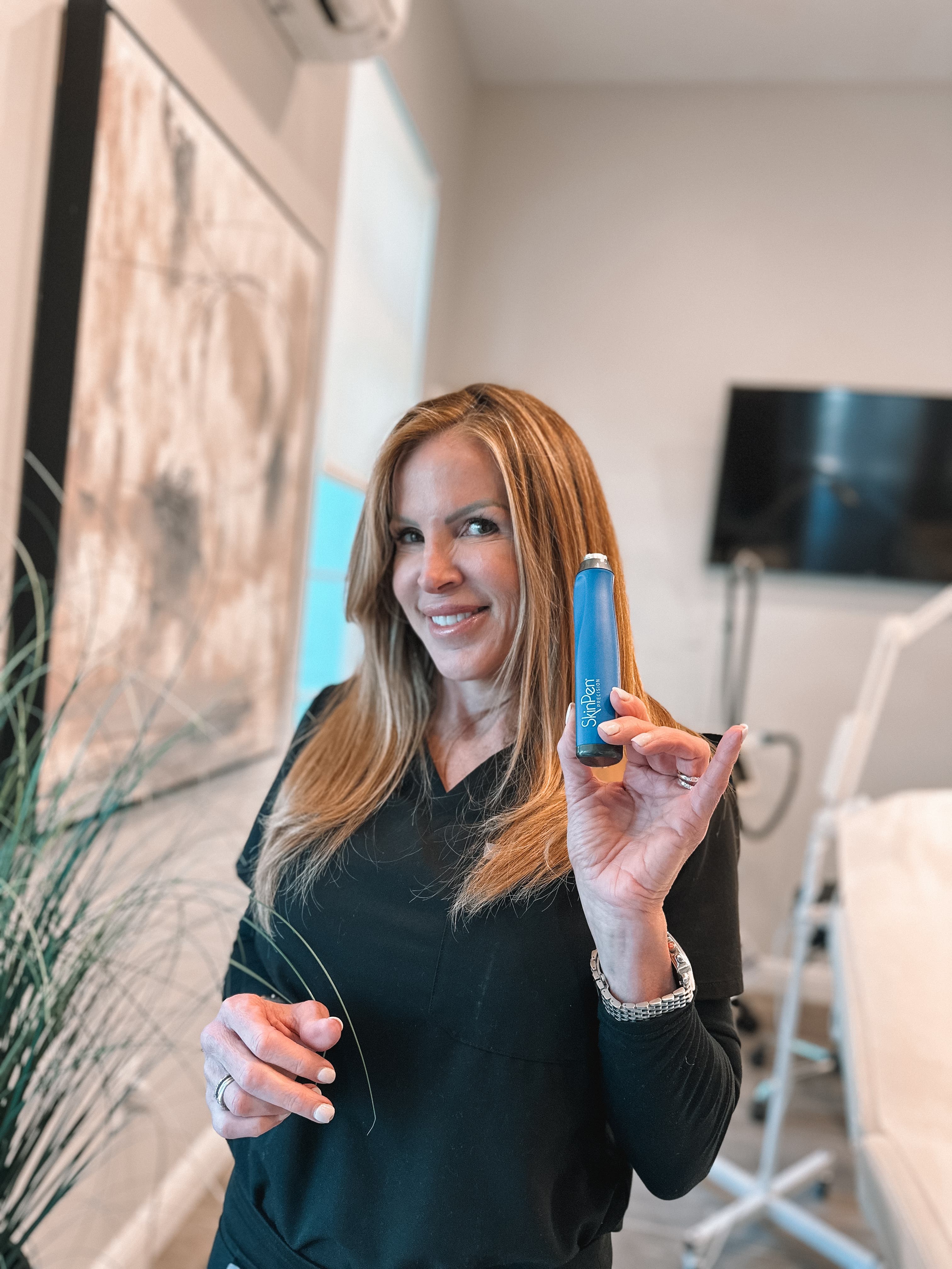 Refresh - Aesthetics & Wellness provider holding a SkinPen microneedling device in a treatment room