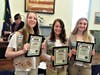 Scouts Allison Quinn left & Reese Reiling right, both recognized for outstanding volunteer service, flank Grace Collins