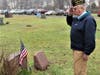 Post Member Sandy Sanderson salutes the grave of a deceased combat veteran after placing a wreath  