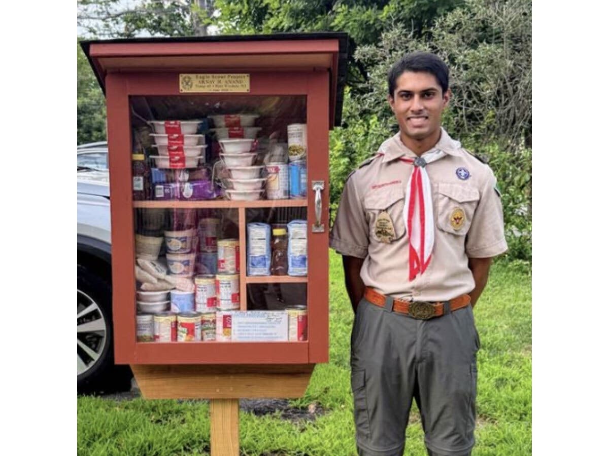 West Windsor student Arnav Anand stands next to a Little Free Food Pantry.