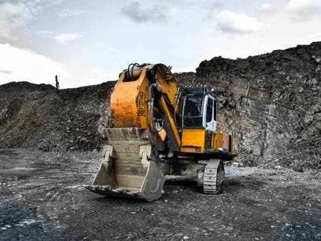 Yellow and black excavator working near a rocky hillside