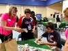 Katie MacKay of Melmark New England explains an activity to Melmark students Tanner Arena (left) and Lucas Garner.