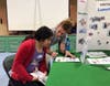 Miah Dunbar of Melmark New England explains an activity to POST Academy student, Veronica Vincent.