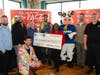Akiem Harshman, center, holds a $1,000 donation check for Judson Baptist Church provided by Quality Dairy and LAFCU, for winning his second annual QD pączki eating contest. Harshman is joined by representatives from LAFCU and QD, along with Laff-e the Cow