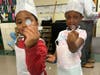 Two Winans Elementary School students proudly hold up their pretend quarters before using them to "purchase" their QD donuts during LAFCU’s Listen & Learn–All About Donuts event.