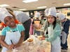 Students at Winans Elementary, dressed in baker attire, decorate their donuts with icing during LAFCU’s Listen & Learn—All About Donuts event, combining creativity with financial literacy.