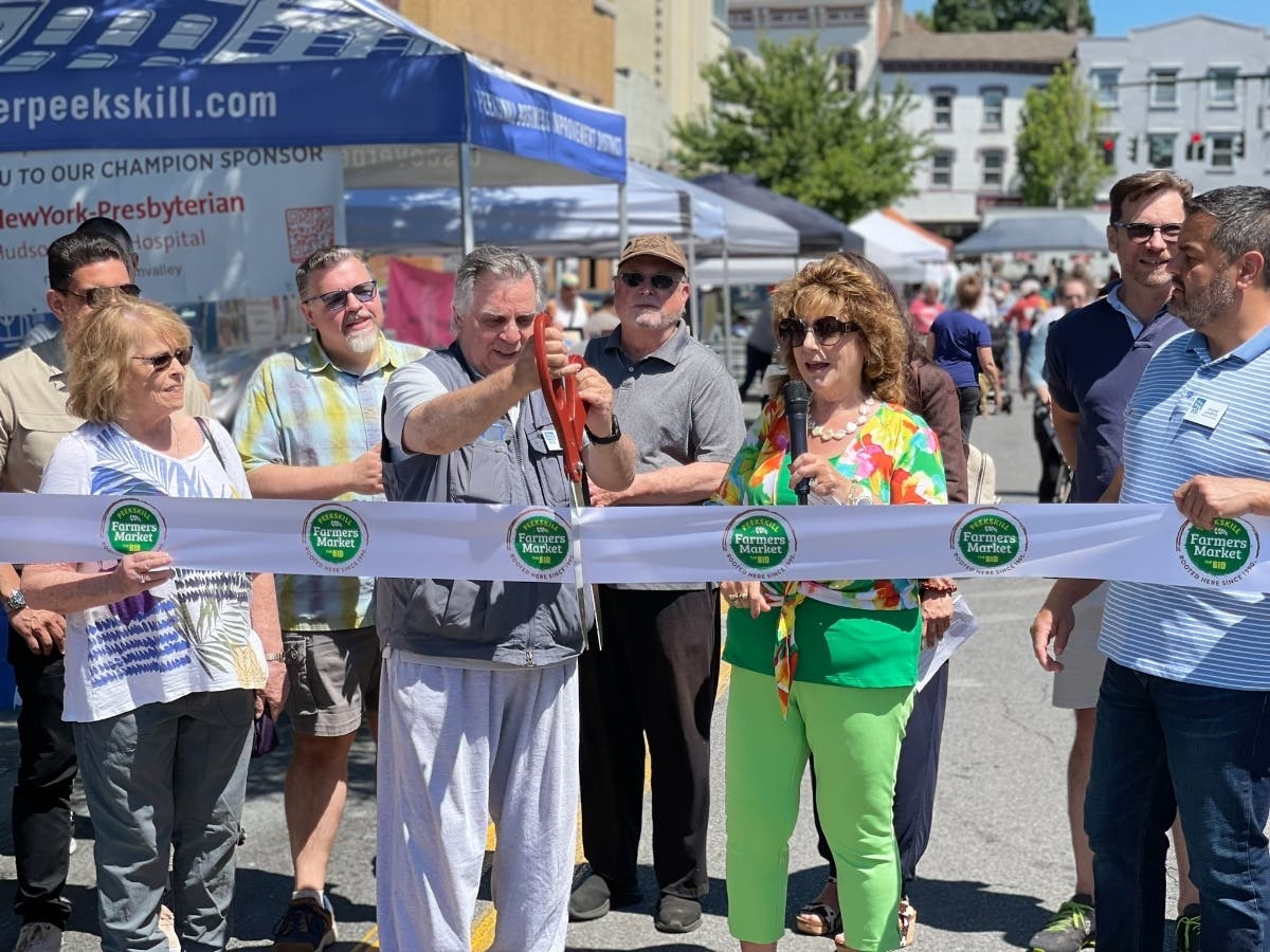 Peekskill BID President Richard Rogers cuts the ceremonial ribbon to the 34th Annual Peekskill Farmers Market as Peekskill Deputy Mayor Patricia Riley and others look on. 