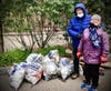 A couple stands next to a pile of trash bags gathered by the Woerd Ave boat launch.