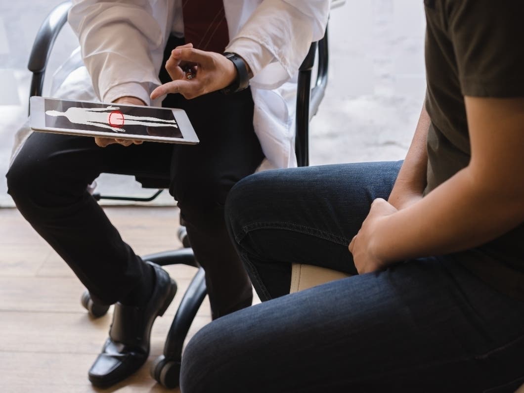 Male doctor and testicular cancer patient are discussing about testicular cancer test report. 