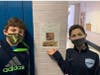 Fifth grade students Will Keigan and Will Baker with a flyer their class made encouraging their classmates to visit Nosh & Grog in Medfield.