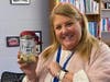 Principal, Holli Caulfield holding the Book Vending Machine coin jar