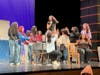 Girls ensemble with Emma Swanson (Sandy) standing on a chair