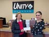 Janice Ballou, Highland Park Community Food Pantry Chair, (left) receives the $1,800 donation from Evrim Cicek, Unity Bank Area Manager.