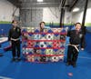 Jedi Warrior students Charlotte, Claudia, and Sam Gonzalez hold up the raffle prize for this week's contest in the Jedi training room at the Academy in Manchester