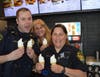 Sergeant Czechowski, Officer Miklitsch and Peg Haacker, Records Clerk, make the cone for the kids.