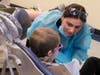 A Midwestern University dental student consults with a young patient during a dental screening at the Give Kids a Smile event.