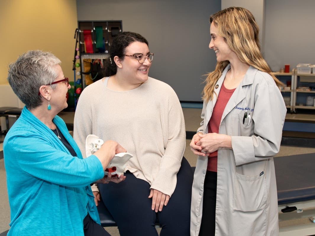 Teri Elliott-Burke, P.T., D.P.T., M.H.S., and Kim McKinnon, D.O., consult with a patient.