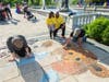 6-year-old Anaya Khandhar and her father Paras Khandhar of West Bloomfield watch as chalk artists draw the Beaumont bear - Beau.