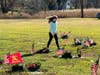 Olivia Beckwith ensures the wreaths are placed properly and gravestones clear of debris.