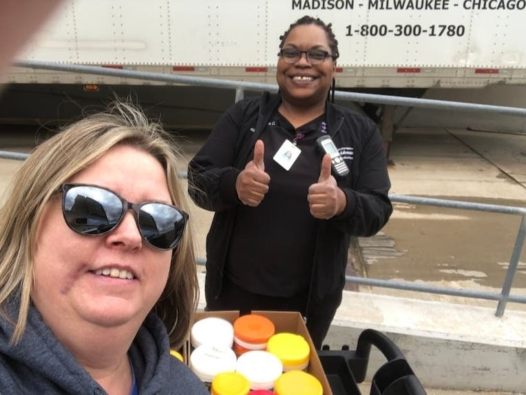 Queen of Martyrs principal Kathleen Tomaszewski (front) hands off the school's stash of disinfectant wipes to a nurse at Christ Hospital.