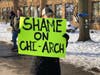 A parent holds a sign criticizing the Archdiocese of Chicago after placing the Queen of Martyrs principal on administrative leave. 