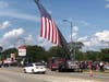 A large American flag hangs from a Chicago hook and ladder truck over 103rd Street for CPD Officer Danny's Golden's homecoming.