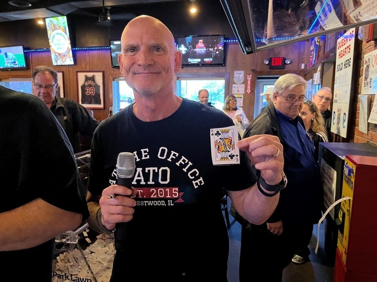The winsome Tim Newsome, owner of At the Office Bar & Grill in Crestwood, holds the King of Clubs picked in the April 17 Park Lawn Queen of Hearts Raffle. 