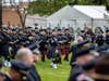 The combined police and fire bagpipes walk across the sprawling lawn of St. Rita as an honor guard prepares to carry the casket of Officer Huesca into the church. 