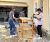 Karthikram Raja (left), Arnav Konda (middle), and Amit Krishna (right), lather the last layer of wood stain onto the first wire 
