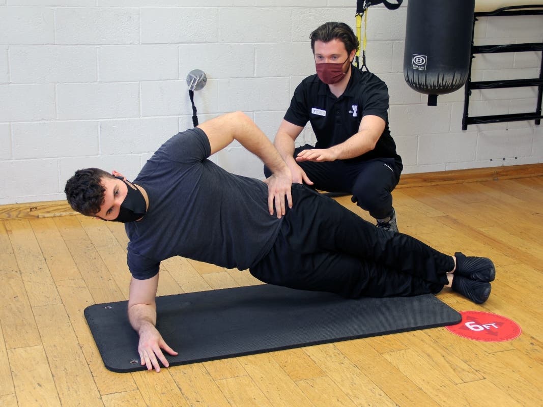 Pictured is college student and Y staff member James Stroud of Madison perfecting a side plank with the coaching of Health and Wellness Director Christian Esola.