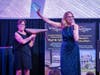Penny Ettinger (rear), Executive Director, NOVA, assists auctioneer Cate Smit (front) with the auctioning of a Nakashima table at NOVA’s SuperNOVA gala which was held on April 3 in Warminster. The gala raised over $200,000 to support of NOVA's mission.