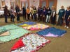 Members of Women of Shir Ami pose with the fleece tie blankets that they made for NOVA clients.  In addition to offering clients physical warmth, the blankets provide emotional comfort, reminding clients that they are cared for and supported.