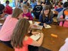 Students color “Kindness matters” buckets on cards for the homeless. 